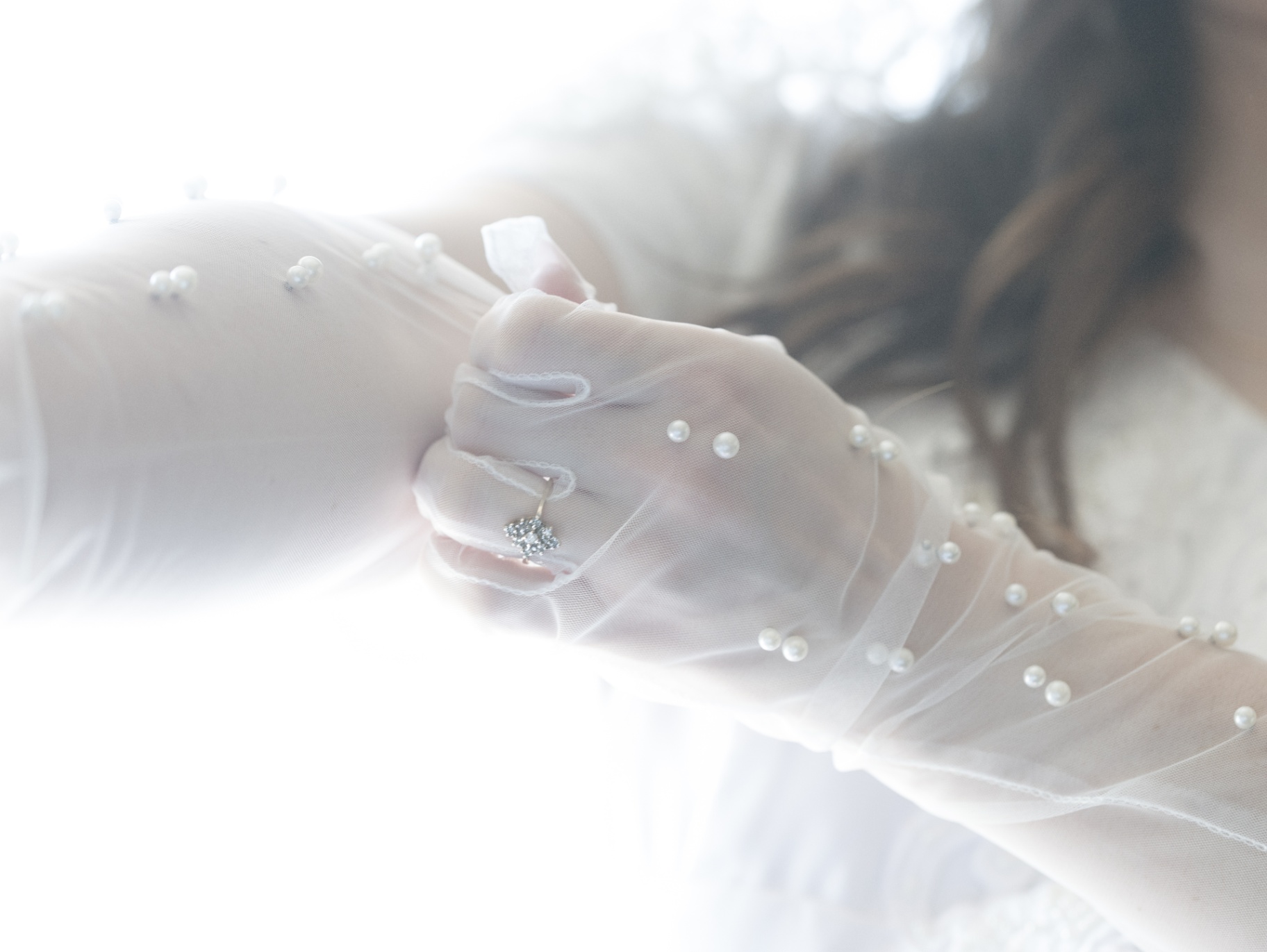 Bride wearing pearl gloves and ring in soft light at L & D Farms
